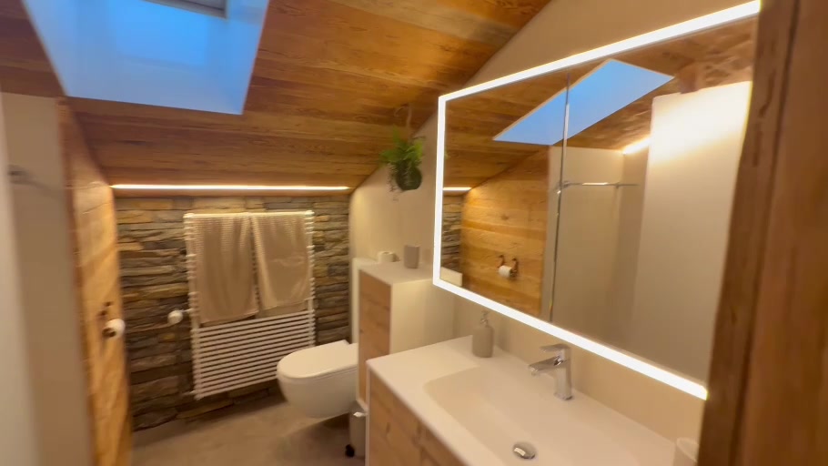 Salle de bains rénovée avec vasque, miroir éclairé et murs en bois